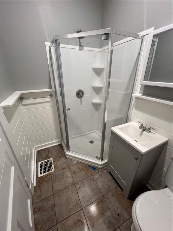 bathroom with tile patterned floors, toilet, an enclosed shower, and vanity