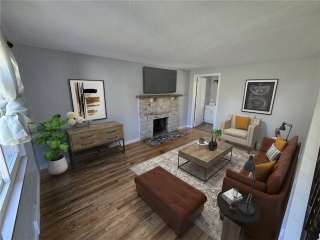 living room with a stone fireplace and dark hardwood / wood-style floors