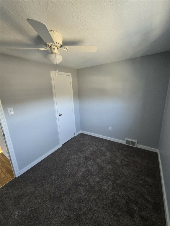 interior space featuring dark colored carpet, a textured ceiling, and ceiling fan