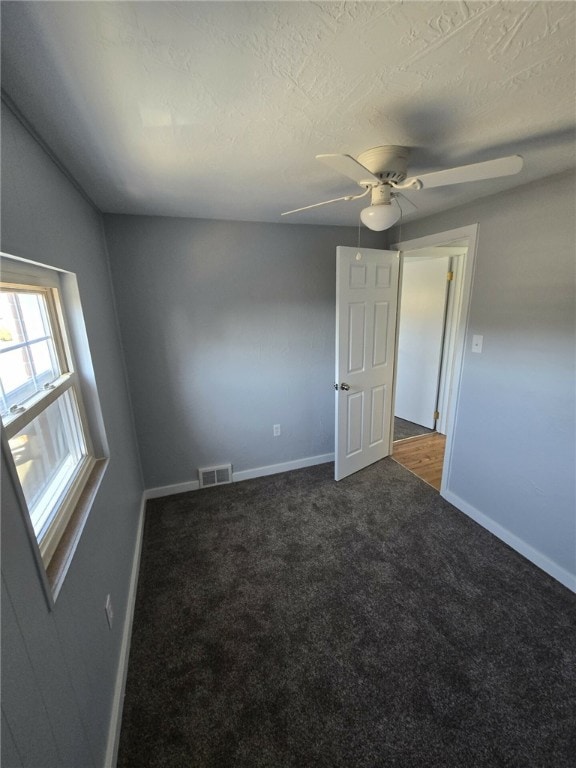 spare room with dark carpet, a textured ceiling, and ceiling fan