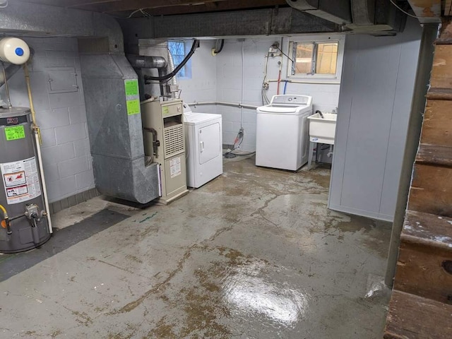 basement with gas water heater, washing machine and clothes dryer, sink, and heating unit