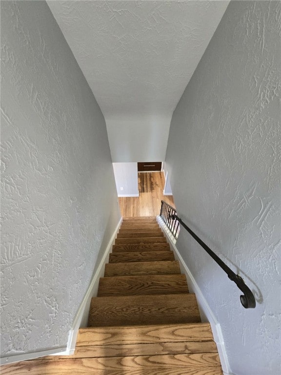 stairway with hardwood / wood-style floors and a textured ceiling