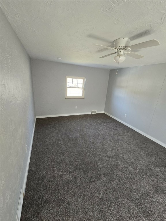 unfurnished room featuring dark carpet, a textured ceiling, and ceiling fan