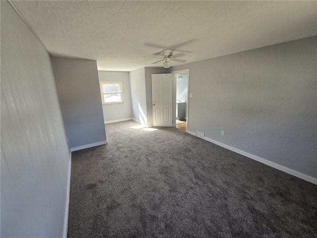 empty room with ceiling fan, a textured ceiling, and dark colored carpet