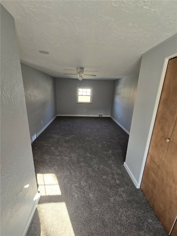 carpeted empty room featuring ceiling fan and a textured ceiling