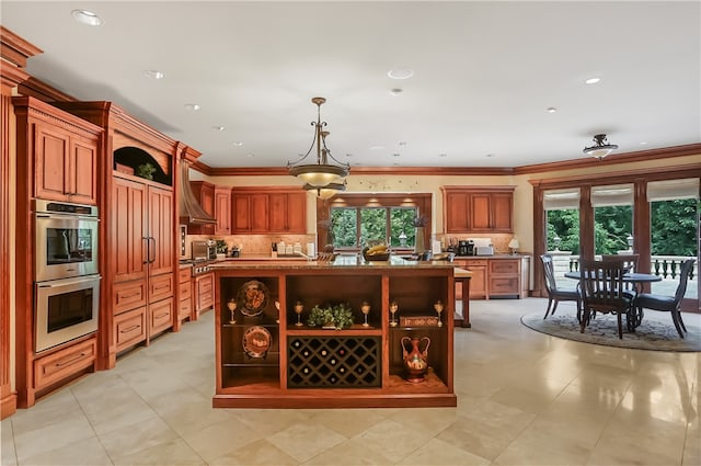 kitchen featuring wall chimney exhaust hood, pendant lighting, crown molding, a kitchen island, and double oven