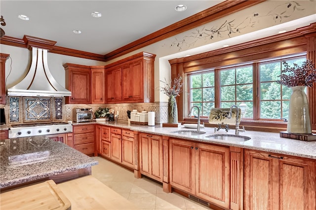 kitchen featuring light stone countertops, tasteful backsplash, sink, stainless steel gas stovetop, and island exhaust hood