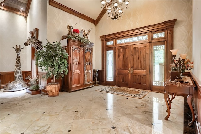 foyer featuring high vaulted ceiling, crown molding, and an inviting chandelier