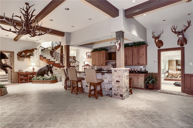 kitchen with a towering ceiling, kitchen peninsula, and beamed ceiling