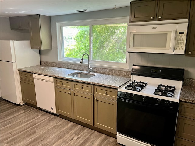 kitchen with white appliances, sink, backsplash, light hardwood / wood-style floors, and light stone counters