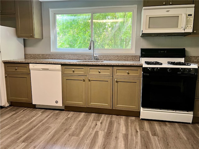 kitchen featuring light stone counters, backsplash, light hardwood / wood-style flooring, sink, and white appliances