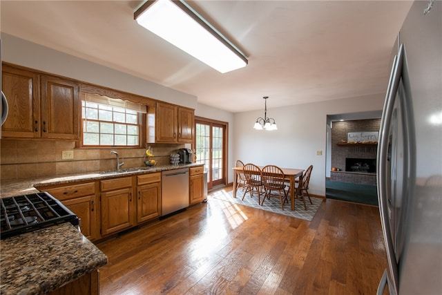 kitchen with pendant lighting, sink, appliances with stainless steel finishes, dark hardwood / wood-style floors, and decorative backsplash