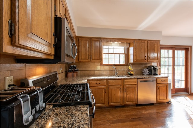 kitchen featuring decorative backsplash, dark wood-type flooring, sink, appliances with stainless steel finishes, and stone countertops