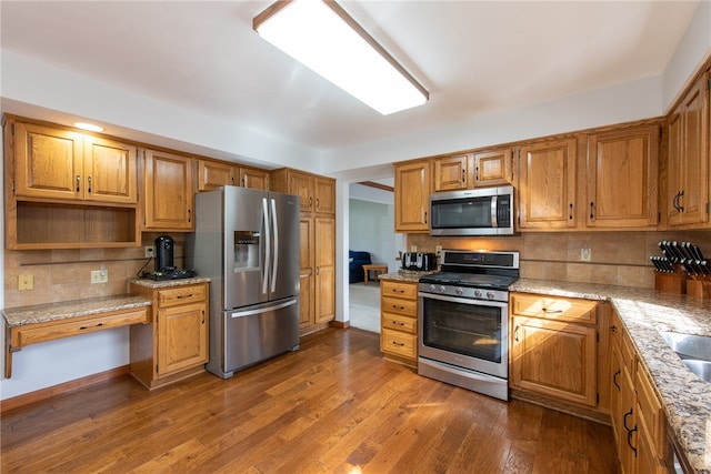 kitchen featuring light stone countertops, appliances with stainless steel finishes, backsplash, and dark hardwood / wood-style floors