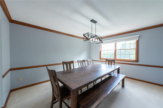 carpeted dining space with crown molding and an inviting chandelier