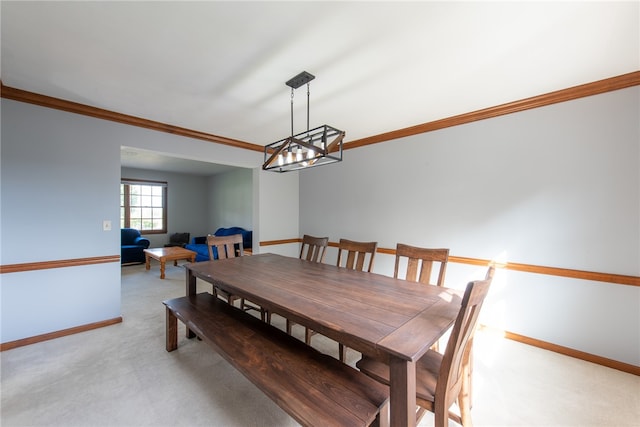 carpeted dining space featuring ornamental molding and a chandelier