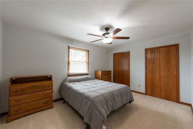 carpeted bedroom with ceiling fan and multiple closets