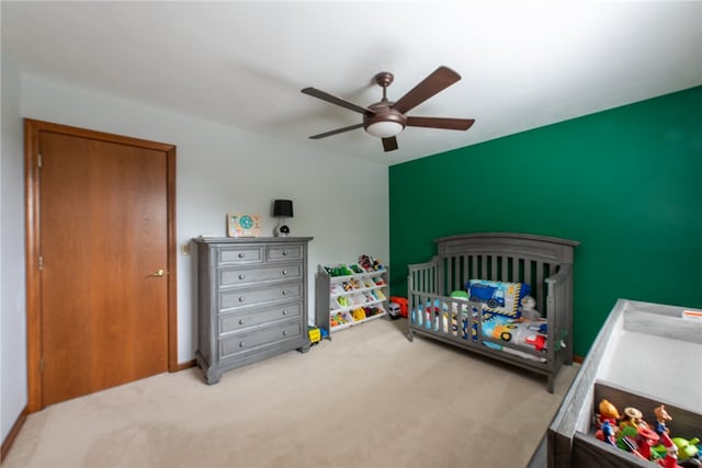 bedroom featuring ceiling fan, a crib, light carpet, and a closet