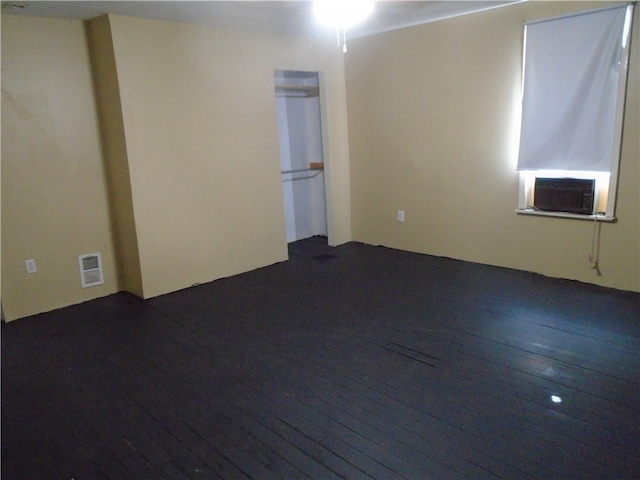 spare room featuring cooling unit and dark hardwood / wood-style flooring