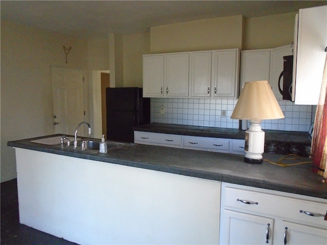 kitchen featuring black fridge, white cabinetry, sink, and tasteful backsplash