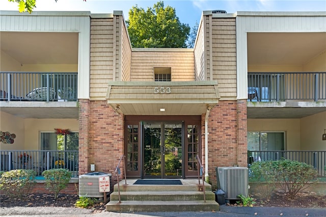 view of exterior entry featuring central air condition unit and a balcony