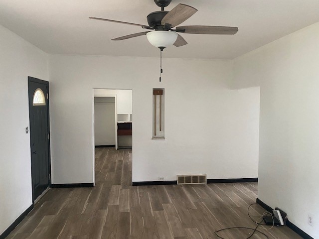 unfurnished room with dark wood-type flooring and ceiling fan