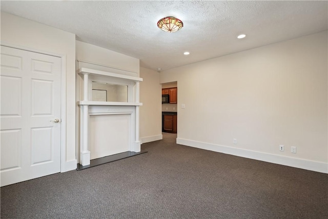 unfurnished living room with dark colored carpet and a textured ceiling