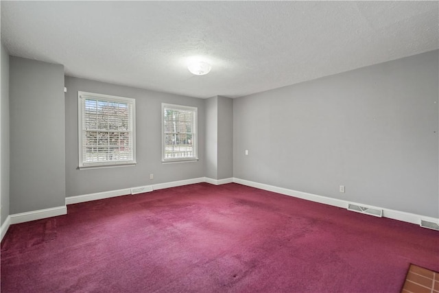 carpeted empty room with a textured ceiling