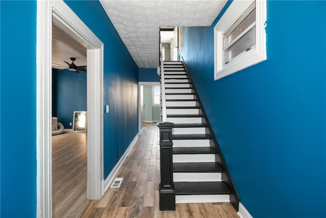 stairs with ceiling fan and hardwood / wood-style floors