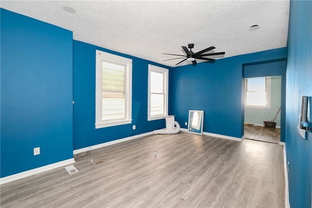 empty room featuring light wood-type flooring, ceiling fan, and a textured ceiling