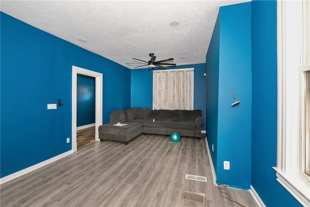 living room featuring ceiling fan, hardwood / wood-style floors, and a textured ceiling