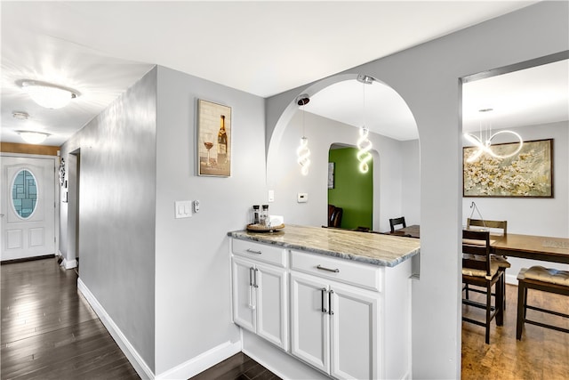 kitchen with pendant lighting, light stone countertops, dark hardwood / wood-style floors, and white cabinetry