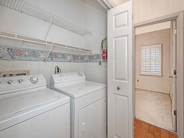 clothes washing area with light hardwood / wood-style floors and washing machine and clothes dryer