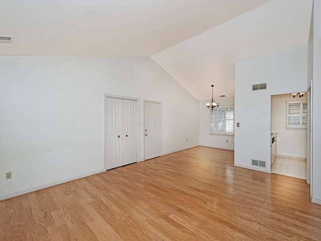 unfurnished living room with light wood-type flooring, vaulted ceiling, and a chandelier