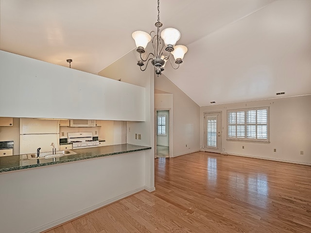 kitchen featuring pendant lighting, white range with gas stovetop, an inviting chandelier, and light wood-type flooring