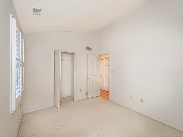 unfurnished bedroom with light carpet, a closet, and vaulted ceiling