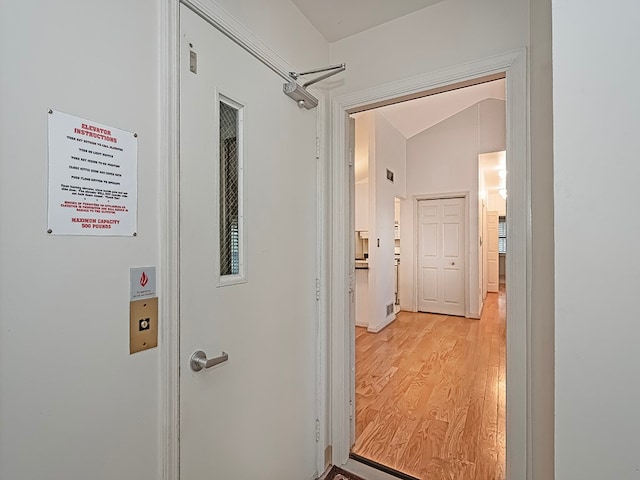 corridor with lofted ceiling and light wood-type flooring