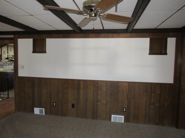 unfurnished room with a paneled ceiling, wood walls, and ceiling fan