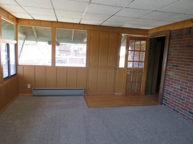 spare room with a paneled ceiling, baseboard heating, and carpet