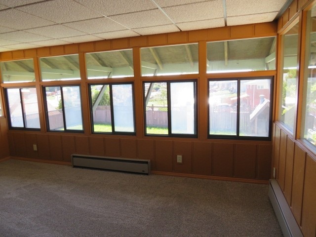 unfurnished sunroom featuring a paneled ceiling and a baseboard heating unit