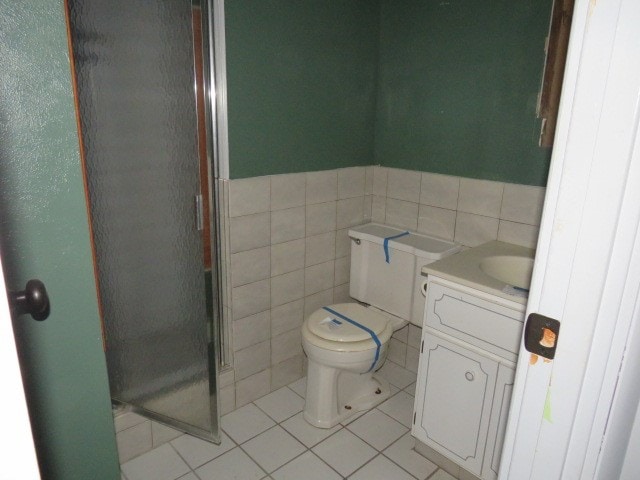 bathroom with tile patterned flooring, vanity, tile walls, and walk in shower