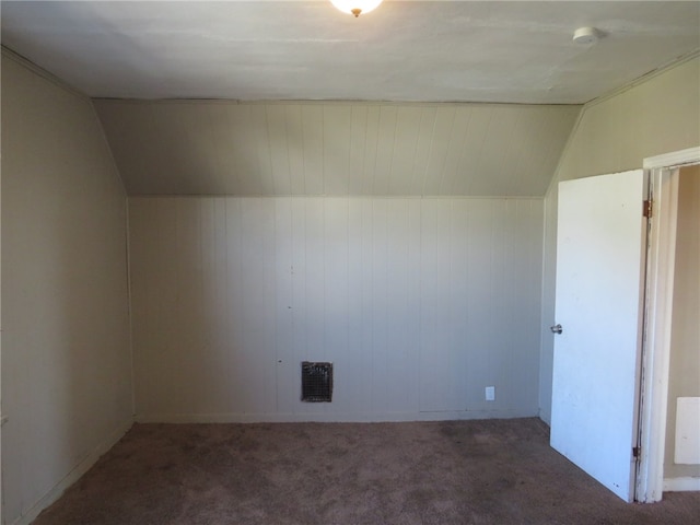 bonus room with lofted ceiling and dark colored carpet