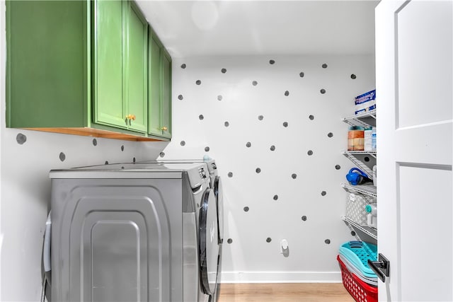 laundry room featuring separate washer and dryer, cabinets, and light hardwood / wood-style flooring