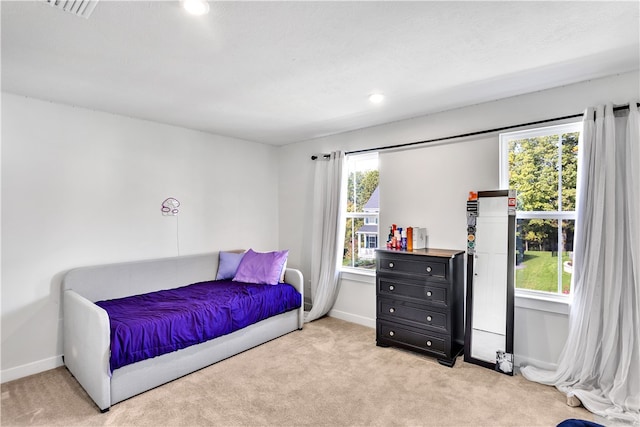 bedroom with multiple windows and light carpet