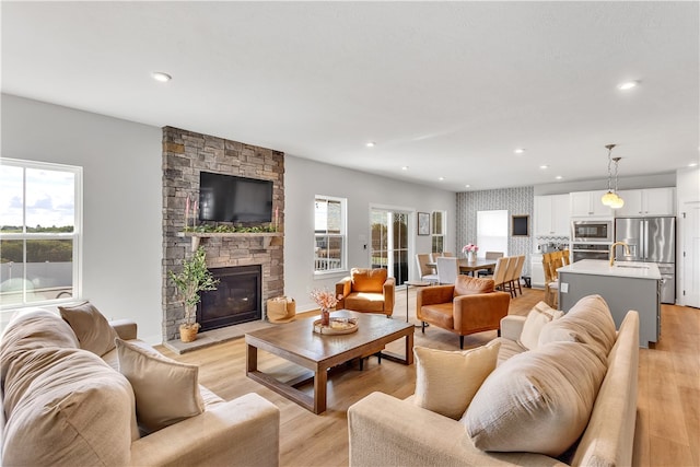 living room with a fireplace, sink, and light wood-type flooring