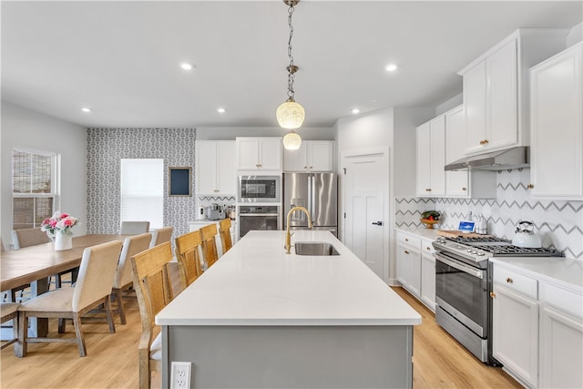 kitchen featuring decorative light fixtures, an island with sink, appliances with stainless steel finishes, and sink