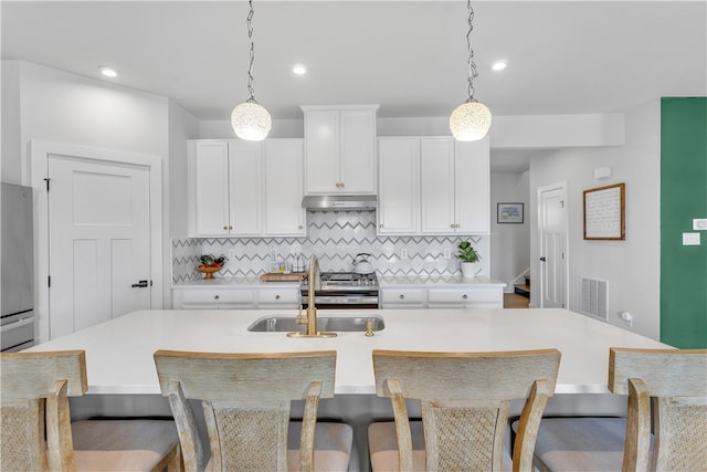 kitchen with backsplash, decorative light fixtures, a center island with sink, and sink