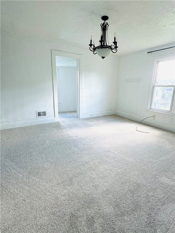 carpeted empty room with an inviting chandelier and a textured ceiling