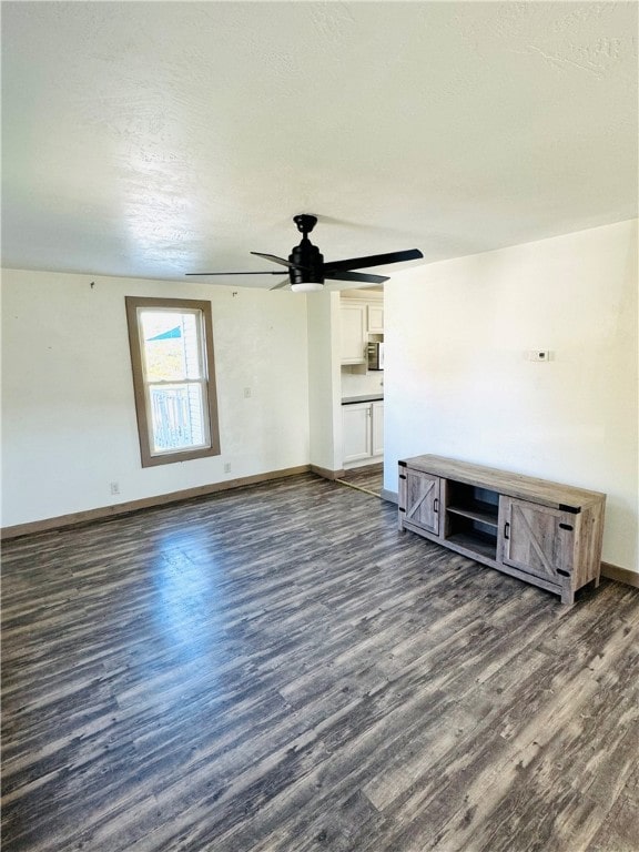 unfurnished living room with dark wood-type flooring, a textured ceiling, and ceiling fan