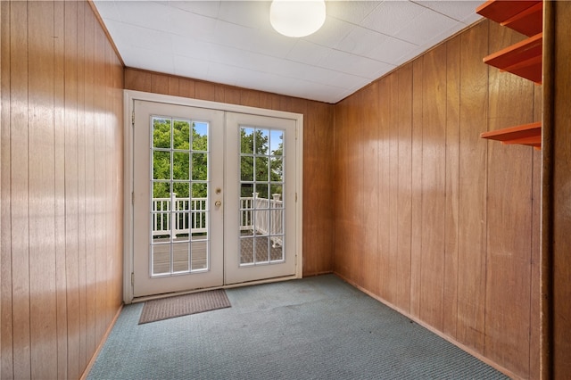 doorway featuring french doors, wooden walls, and light carpet